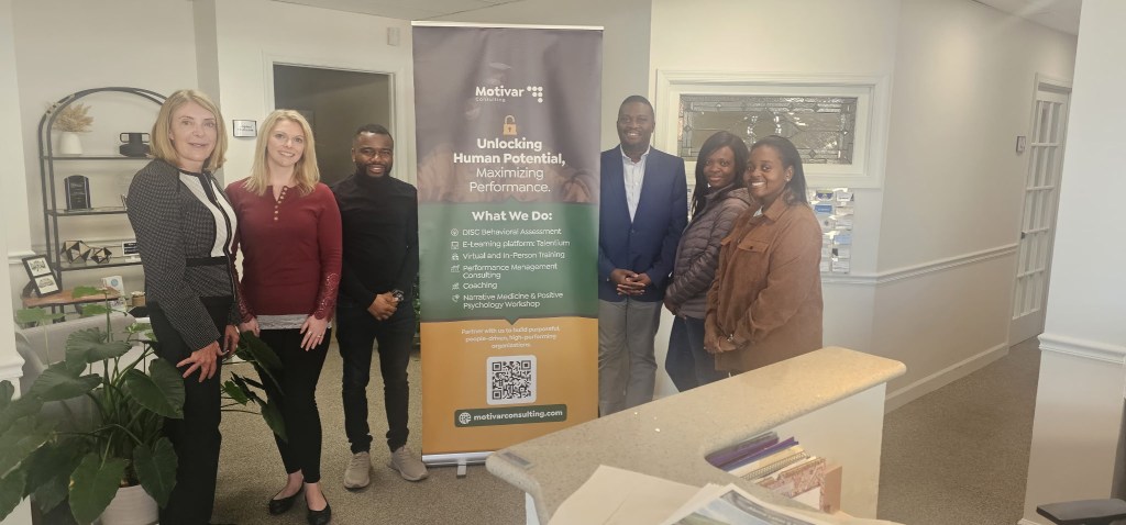 A group of participants at the Talbot Business Workshop, posing next to a banner for Motivar Consulting that highlights services focused on human potential and performance.